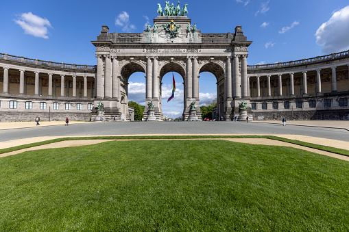 Brussels, Belgium - May 16, 2023: Central Cinquantenaire arch and U-shaped arcade in Cinquantenaire Park. Rainbow flag (LGBT) flies on the building