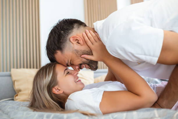 Beautiful loving couple kissing in bed. beautiful young couple lying together on the bed. Beautiful loving couple kissing in bed. beautiful young couple lying together on the bed. seduction stock pictures, royalty-free photos & images