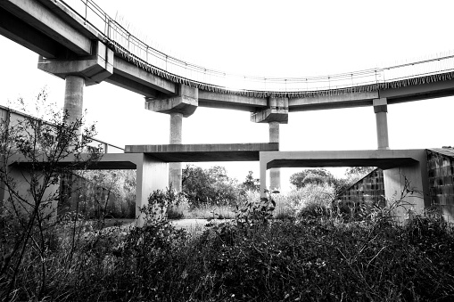 a low angle photograph of a three section culvert juxtaposed against a pedestrian overpass showing an interesting assemblage of different lines, levels, and layers, shot in Palmerston city in the Northern territory, Australia