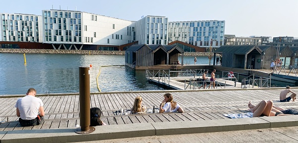 The photo was taken on May 26th, 2023 in a new fashionable district by the sea in Nordhavn, Copenhagen, Denmark. Residential apartments are mixed with office buildings and business making the area  attractive and very much alive. Luxury apartment buildings can be seen in the background