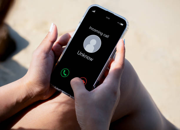 Incoming call with unknown caller, malicious phone calls concept. Unknown number displayed showing on smart mobile phone in woman hand on leave day at the beach. Spam and robocalls, scam call alert. llamada entrante con llamador desconocido, concepto de llamadas telefónicas maliciosas. número desconocido que se muestra en el teléfono móvil inteligente en la mano de la mujer en el día de licencia en la playa. spam y llamadas automáticas, alerta d