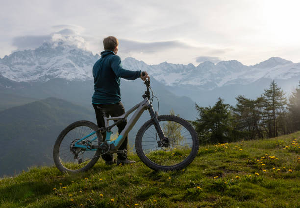 istock Young man pauses on mountain meadow with electric bicycle 1494204751