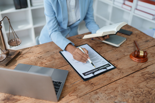 Young African American lawyer studying a case for a client and signing a legal contract to fight her opponent in court. Legal and lawyer concepts