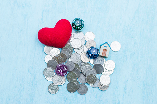 Astrology dice with red heart and miniature house on baht coin with space on blue texture background, love wealth and success fortune telling