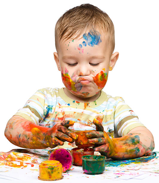 Very messy boy having fun covering himself with paints stock photo