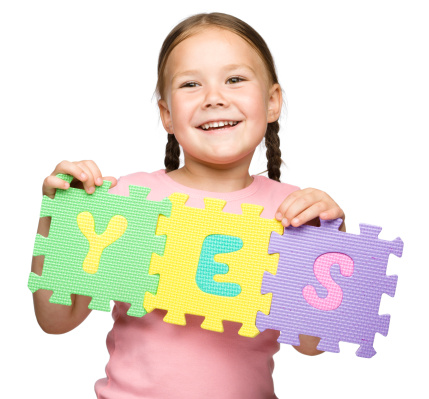 Cute little girl is holding Yes slogan, isolated over white