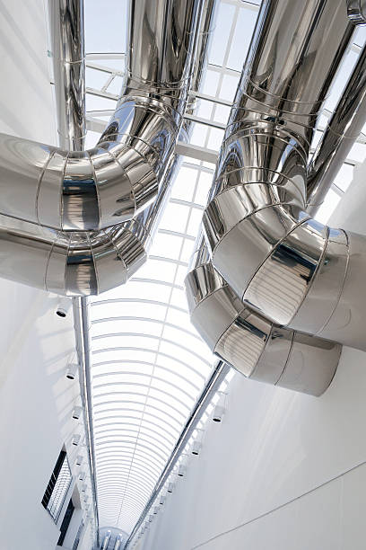 Shiny silver air conditioning ducts against a white wall stock photo