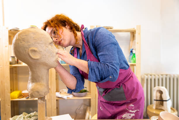istock Female sculptor working in pottery studio workshop sculpting human head. 1494221002