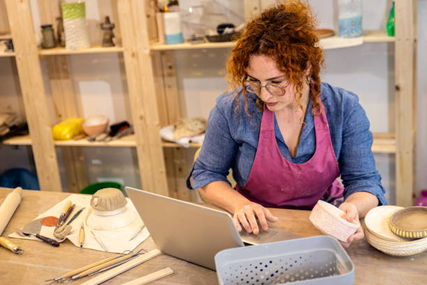 istock Female business owner using laptop in pottery studio workshop. 1494221044