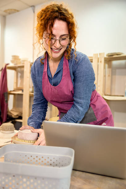 istock Female business owner using laptop in pottery studio workshop. 1494221057