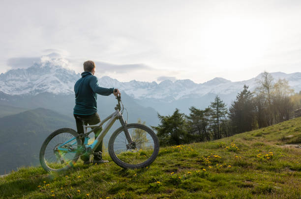 Young man pauses on mountain meadow with electric bicycle