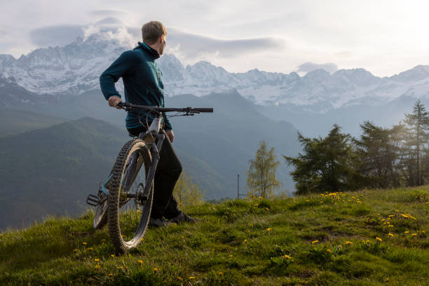 istock Young man pauses on mountain meadow with electric bicycle 1494221469