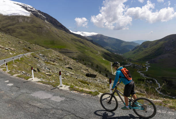 istock Young woman rides e-bicycle on mountain road 1494223674