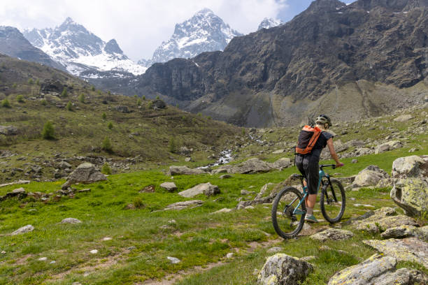 istock Young woman rides e-bicycle up mountain trail 1494224047
