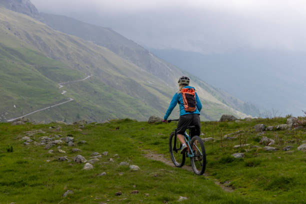istock Young woman rides e-bicycle up mountain trail 1494224101