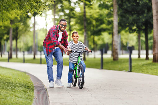 Happy family  father teaches boy son  to ride bike in  park   in nature