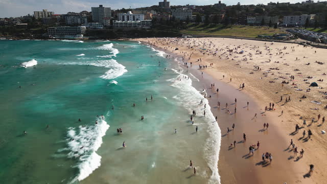 4K Aerial view Footage of Crowd people visiting and relaxing at iconic Bondi Beach with sunshine during the summer weekends in Sydney