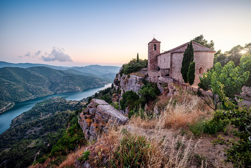 Siurana reservoir during the summer, view of the medieval village of Siurana with the river full.  Church of Santa Maria at sunset, Catalonia, Spain