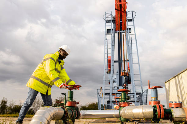 trabajador del campo petrolero cerrando la válvula industrial por la plataforma petrolera que controla la producción. - valve air valve oil field oil fotografías e imágenes de stock