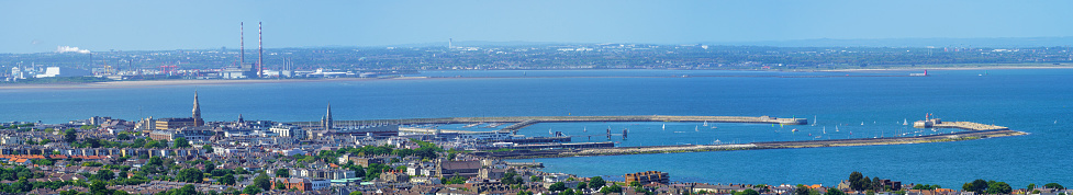 Panoramic wide view of Dun Laoghaire and Dublin city skyline, with Dun Laoghaire harbour in the foreground, on a sunny summer day, and the Poolbeg chimneys in the distance