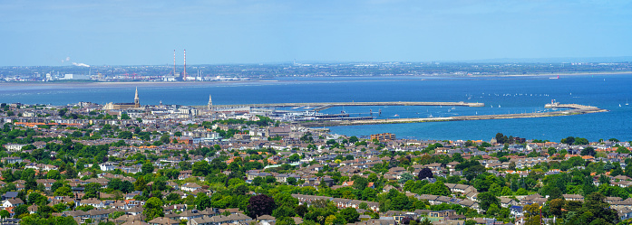 Wide panoramic view of Dun Laoghaire and harbour, at Dublin bay, on a sunny summer day, and the Poolbeg chimneys in the distance