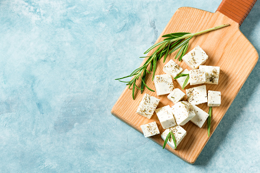 Fresh Greek Feta Cheese. Healthy ingredient for cooking salad. Chopped Goat feta cheese with rosemary herbs, copy space.