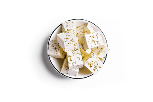 Crumbled young cow cheese pieces on a pile on white background