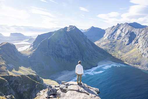 Young man hiking in a beautiful scenery in Summer enjoying nature and the outdoors.\nLofoten islands, Norway