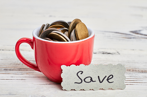 Coins in cup on wood. Save money for romantic dream.