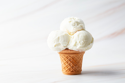 Vanilla ice cream scoop in a serve waffle cone on a white background, copy space.