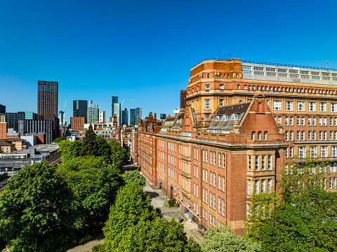 An aerial photograph of the Victorian Sackville Street buiding set against the more modern urban architecture in Central Manchester, England. The photograph was produced on a bright sunny day with clear blue skies