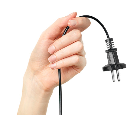 a female hand holds a power cable with an electric plug on a white isolated background