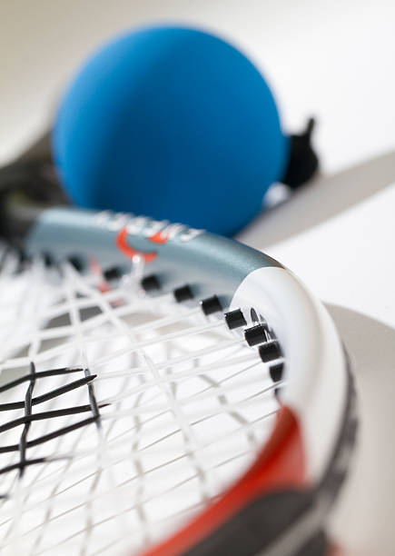 Raquetball Close Up Blue racquetball blurred near handle. Part of strings and racquet are in focus. View from head of racquet. racketball stock pictures, royalty-free photos & images