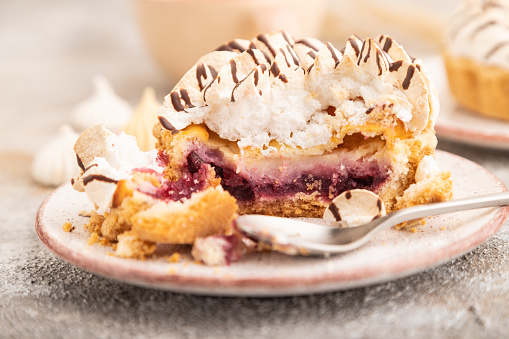 Two tartlets with meringue cream and cup of coffee on brown concrete background. side view, selective focus. Breakfast, morning, concept.