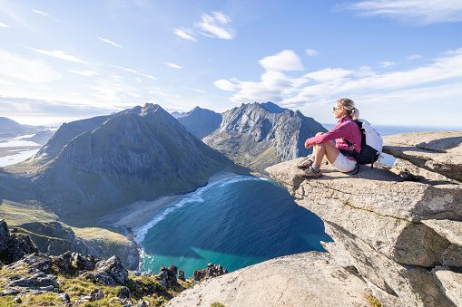 Young woman hiking in a beautiful scenery in Summer enjoying nature and the outdoors.\nLofoten islands, Norway