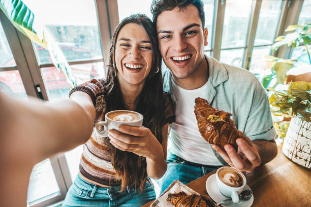 glückliches paar genießt das frühstück und trinkt kaffee in der bar-cafeteria - lifestyle-konzept mit verliebten männern und mädchen, die sich im restaurant im stadtzentrum verabreden - espresso men coffee shop drinking stock-fotos und bilder