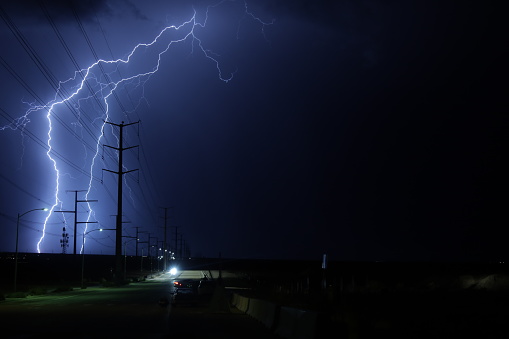 A lightning bolt strikes and fractures behind powerlines on the edge of the city in North Las Vegas.