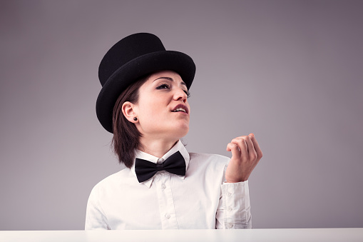 Superb and vain woman personifies Stereotypical, personified image of an arrogant, vain woman: wearing a top hat, white shirt, necktie, dismissively blowing on her manicure, mocking us. She isn't just