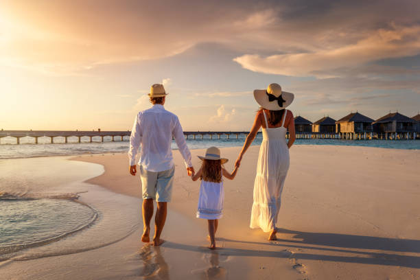 istock Afamily on summer holidays walks down a beach during sunset time 1494249278