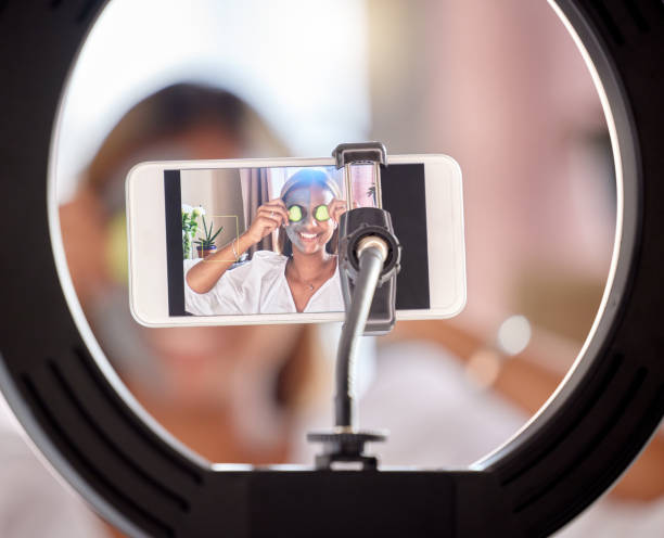 istock Live streaming, phone and woman in ring light for skincare tutorial, influencer or online social media post at home. Happy female vlogger smile in beauty face mask for internet vlog or mobile podcast 1494250480