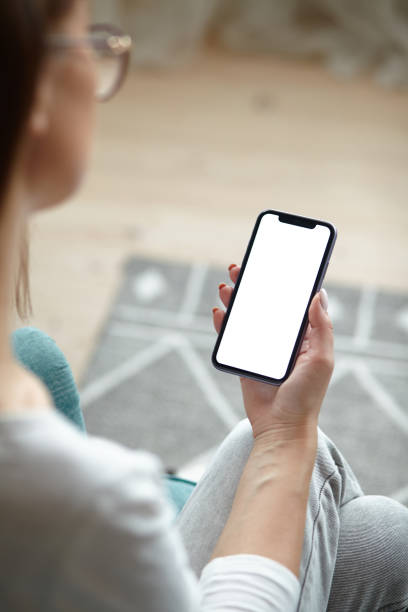 istock Mock up white screen blank mobile phone in woman hands holding Back view 1494251802