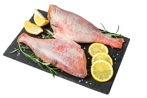 Fresh fish sebastes and ingredients for cooking. Raw gutted fish with spices and herbs on black slate isolated on white background