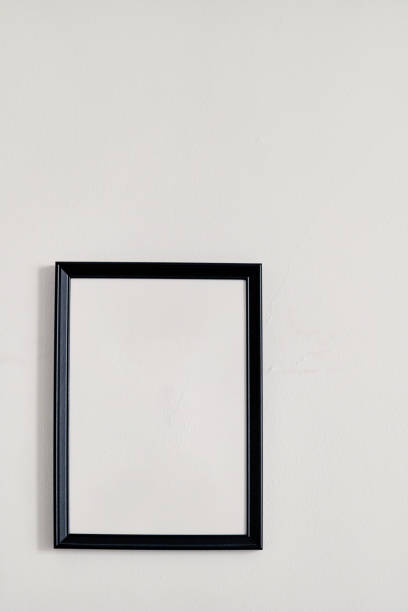 istock An empty photo frame with a black border hanging on a white wall 1494252309