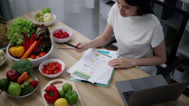 Young female Nutritionist working on laptop with healthy fruit and vegetable