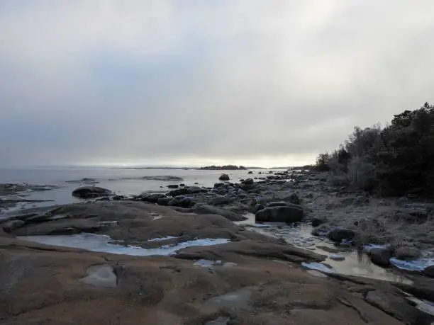 A scenic beach featuring a rocky shoreline with large chunks of melting ice from the ocean water lapping against it