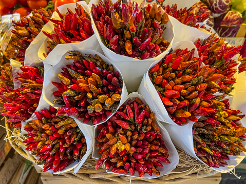 The Venice Rialto Market: Large canal front covered area with stalls trading with fresh fish, seafood, vegetables and fruits. Food background with copy space. Dried red pepper bunches wrapped in white paper cones