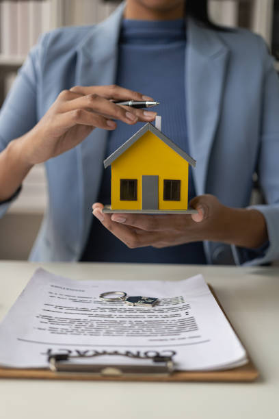 un agente de bienes raíces ofrece una casa a un hombre de negocios que firma un trato. para consultores de seguros de hogar, inversiones inmobiliarias, seguros de propiedad... - real estate mortgage document key contract fotografías e imágenes de stock