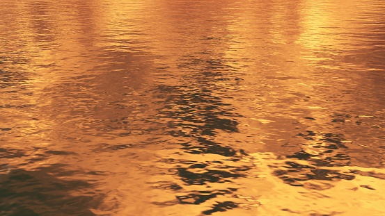 Glossy golden water surface with liquid wavy ripples. Abstract luxury natural background in warm yellow and orange sunset colors 3D illustration.
