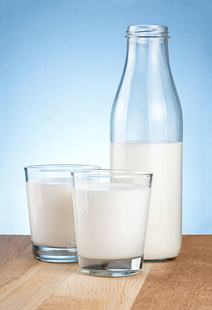 istock Half Milk bottle and two glass is wooden table 149425869