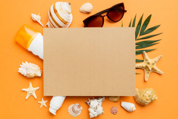 istock Summer time concept with blank greeting card and blank craft paper on colored background. Seashells from ocean shore in the shape of frame separated with space for text top view 1494258753